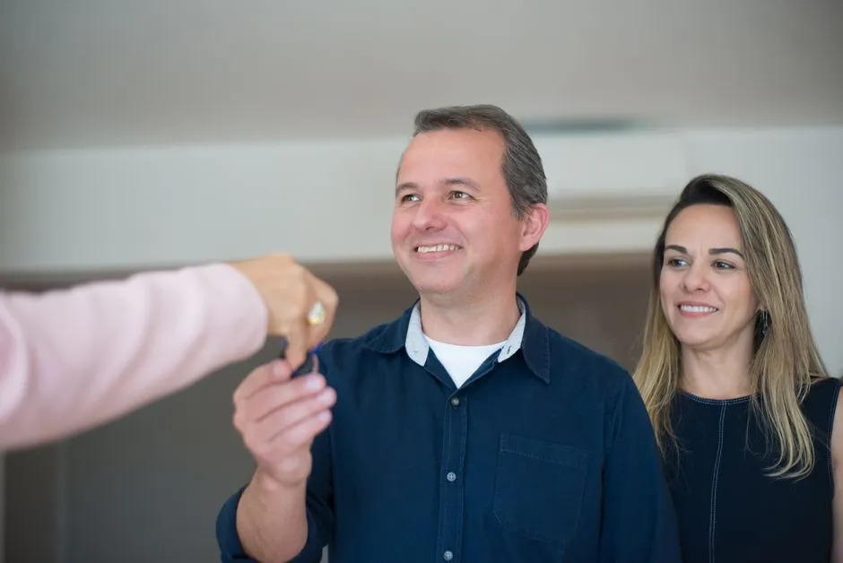 A renter receiving keys from a landlord after a lease is signed, illustrating the moment a voucher holder moves into a private rental unit